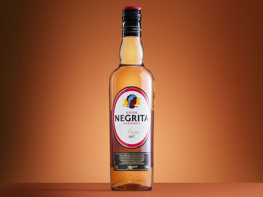 A bottle of Negrita Bardinet rhum against a gradient brown background, with a red and white label displaying the brand logo and text.