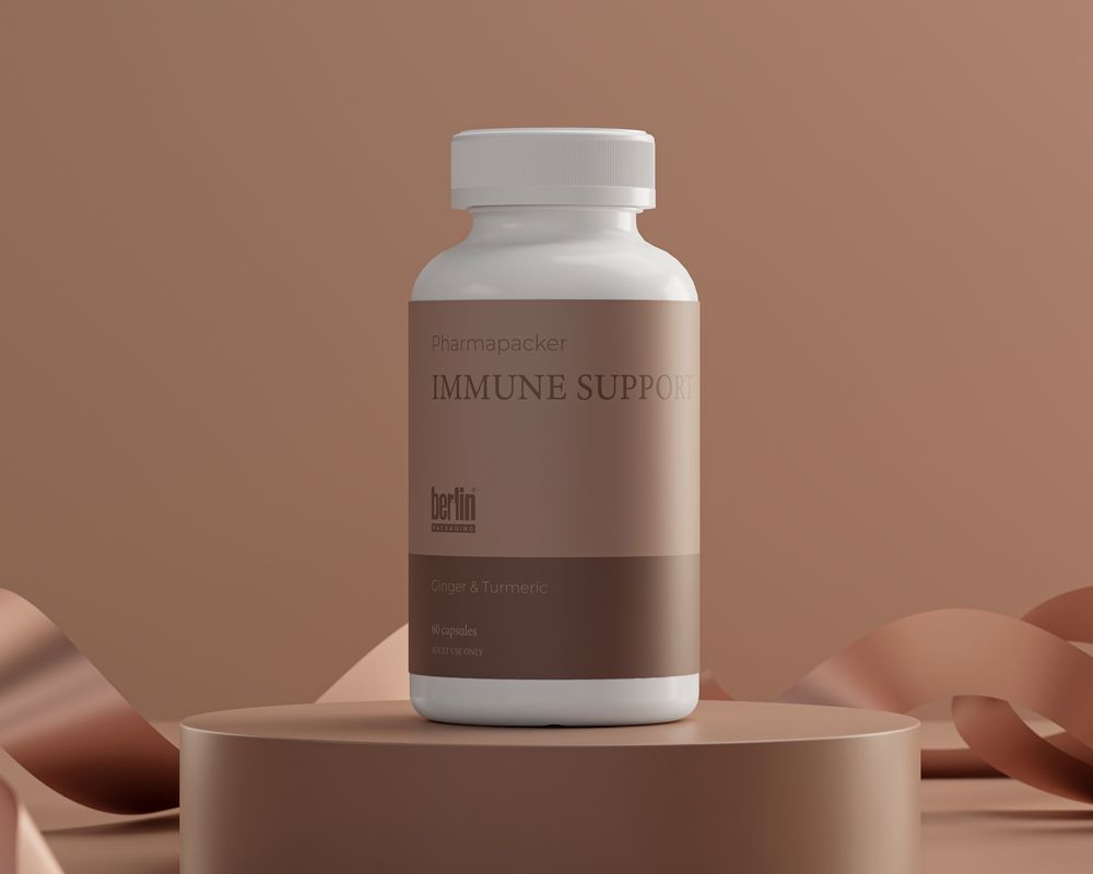 A bottle of Immune Support capsules with a beige label on a pedestal, surrounded by ribbon against a brown background.