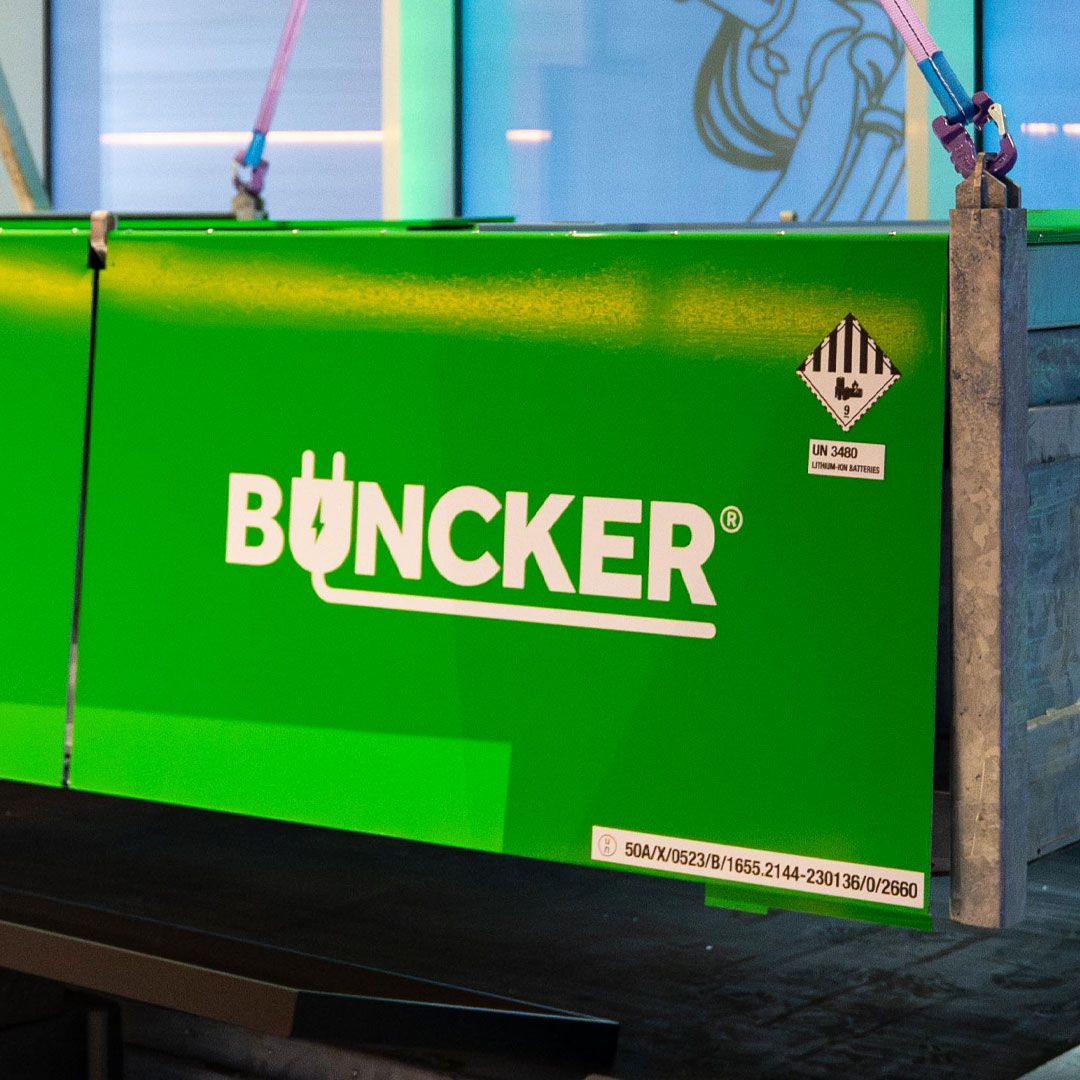 Green container with "Buncker" logo and UN 3480 label for lithium-ion batteries, secured with straps.