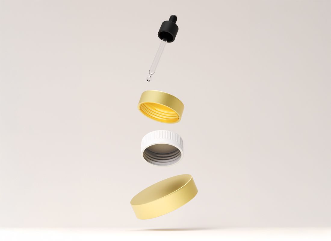 Floating dropper and gold, white, and black bottle caps arranged vertically against a plain background.