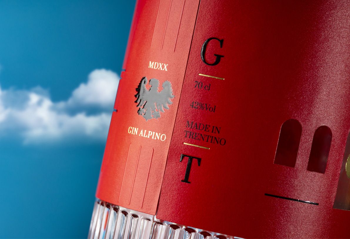 Belleville Ribs glass bottle for spirits by Berlin Packaging customized by Killer Idea, close-up of red label with embossed details, gold accents and printed text elements, highlighting premium packaging design within the Ginnasium project.