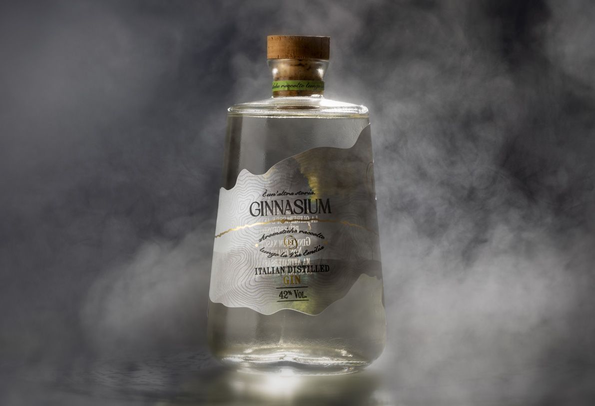 Alchemist 700 ml glass bottle for spirits by Berlin Packaging customized by Rewot creative agency, created for the Ginnasium project, featuring a chemistry-inspired silhouette, cork closure and shaped, textured label with hot stamping details.