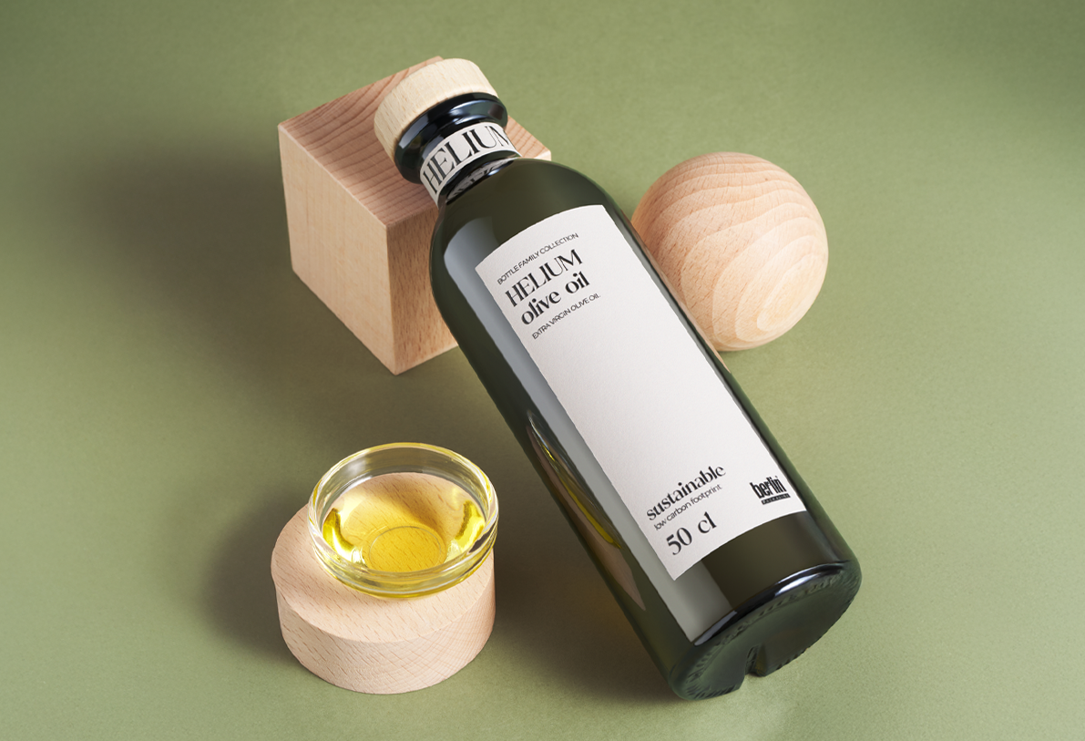 Close-up of Helium olive oil dark glass bottle with minimalist label and a small bowl of golden olive oil on wooden blocks.