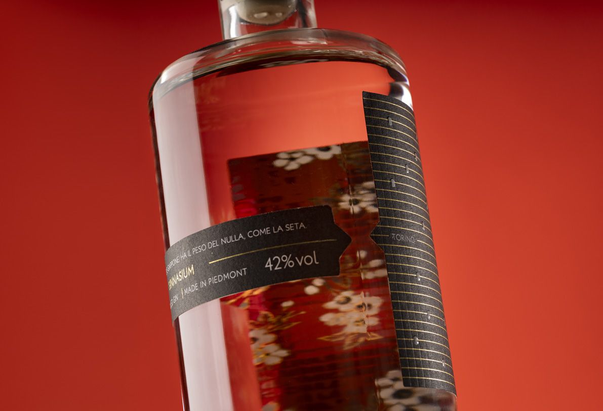 Close-up of black and gold label from Jundo 700 glass bottle for spirits by Berlin Packaging customized by Mark Design, created for the Ginnasium project, set against a vibrant red background.