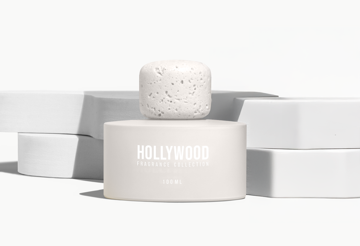 BP_EM_INTERNATIONAL_NEWS_HOLLYWOOD_let'sstart Single Hollywood Fragrance Collection perfume bottle with matte finish and stone-inspired cap, displayed on white sculptural blocks. Minimalist luxury fragrance design.