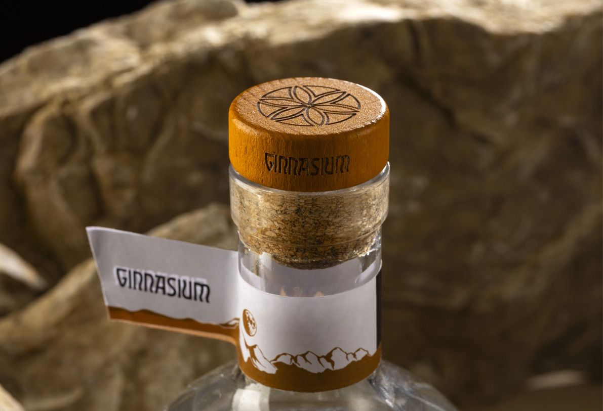 Nocturne Ribs glass bottle for spirits by Berlin Packaging customized by Redfish design agency, created for the Ginnasium project, detail of engraved cork closure and neck label with graphic elements, with rock surface in the background.
