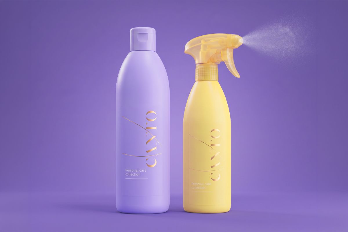 Two personal care bottles on a purple background, one lavender with a flip cap and one yellow spray bottle emitting mist.