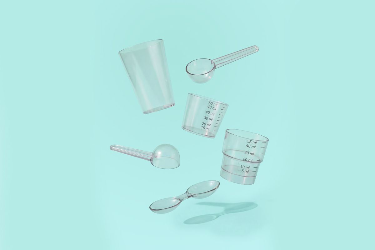 Floating transparent measuring cups and spoons against a light teal background.