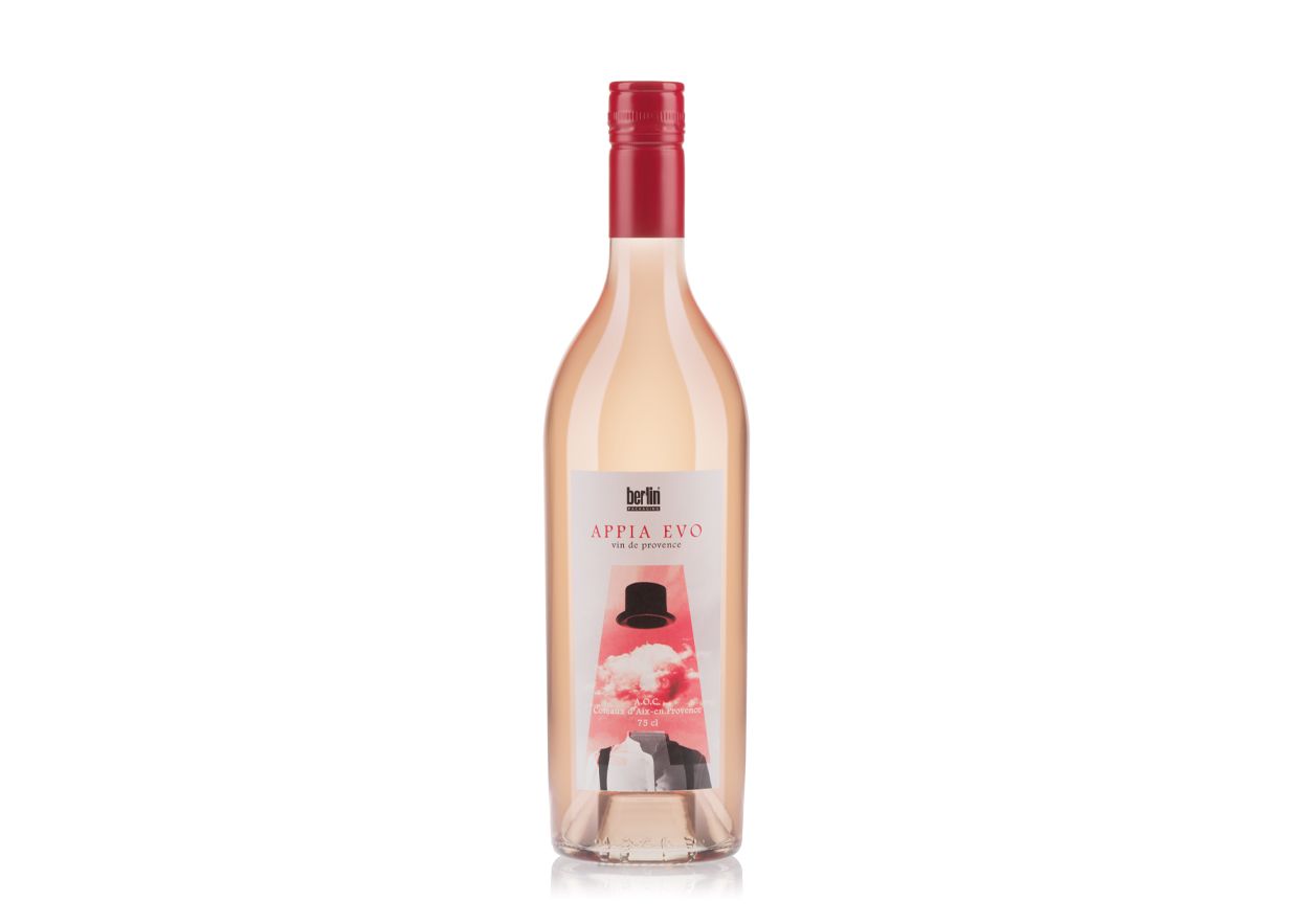 Appia Evo bottle by Berlin Packaging filled with rosé wine, featuring a red cap and a label with a surreal image of a floating hat and clouds.