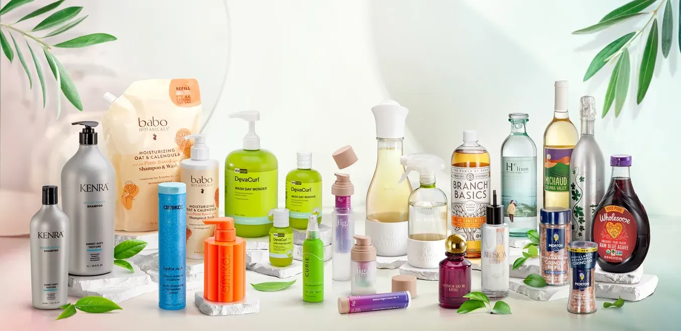 A variety of skincare and wellness products displayed on a surface, surrounded by green leaves, with a light background.