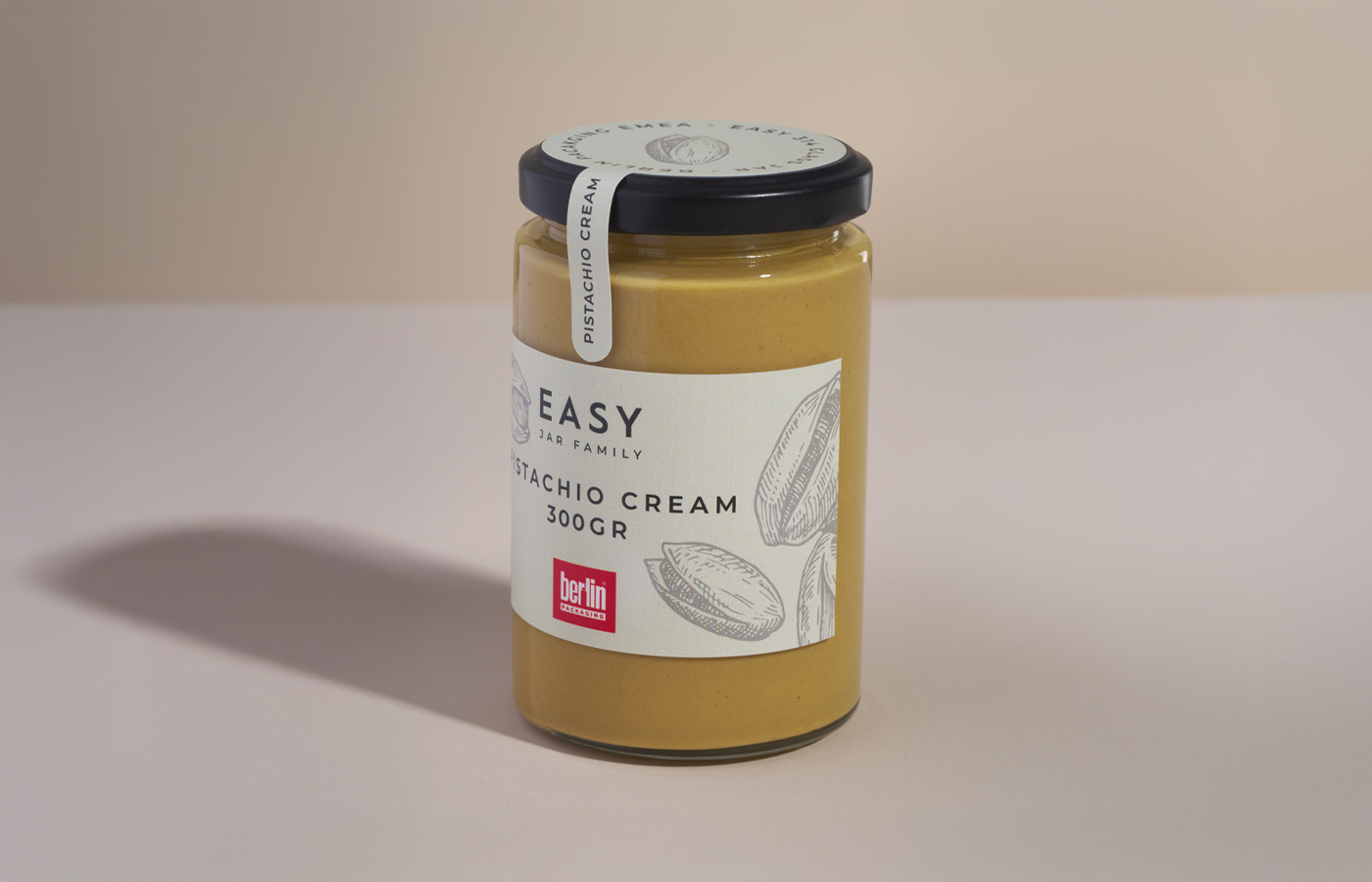 BP_EM_NEWS_EASY_JARS_300TREQUARTI Close-up of a 300-gram pistachio cream jar from the Easy Jar Family collection, featuring a white label with pistachio illustrations and a black lid.