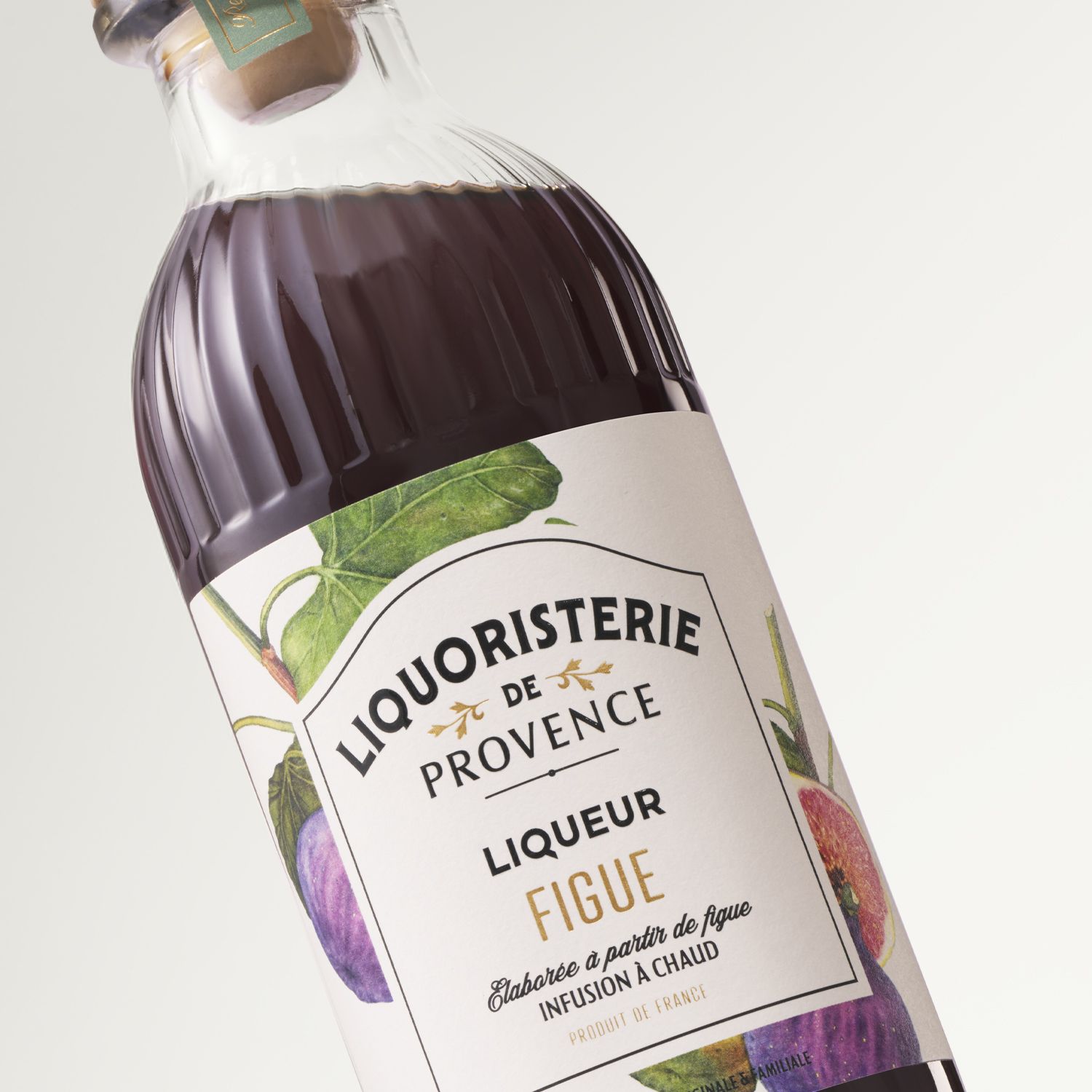 Helium Ribs bottle by Berlin Packaging for Liquoristerie de Provence, Liqueur Figue with a fig illustration on the label, set against a white background.