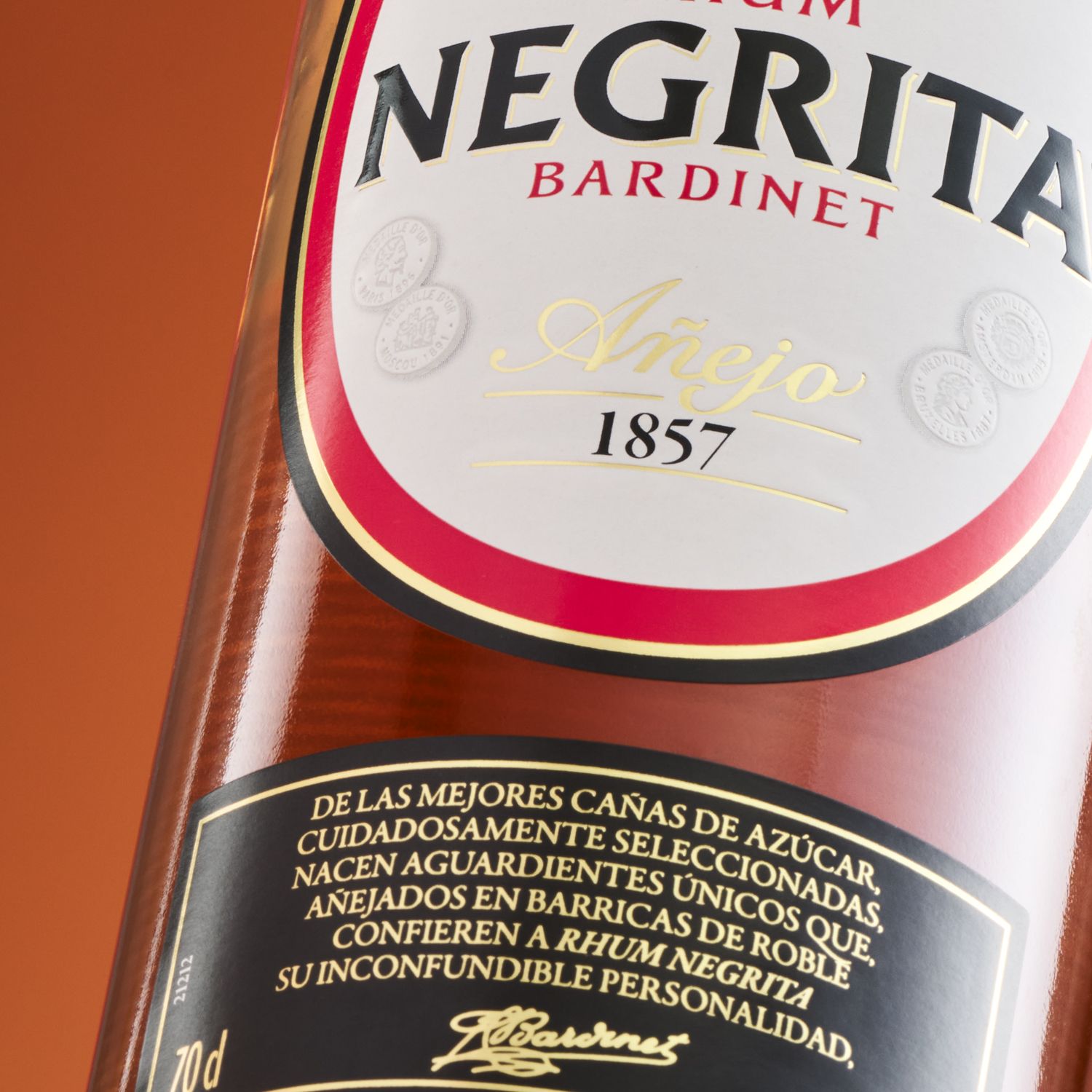 Close-up of Bardinet Negrita rhum bottle label with "Añejo 1857" in gold script, showcasing branding and details in Spanish against a warm backdrop.