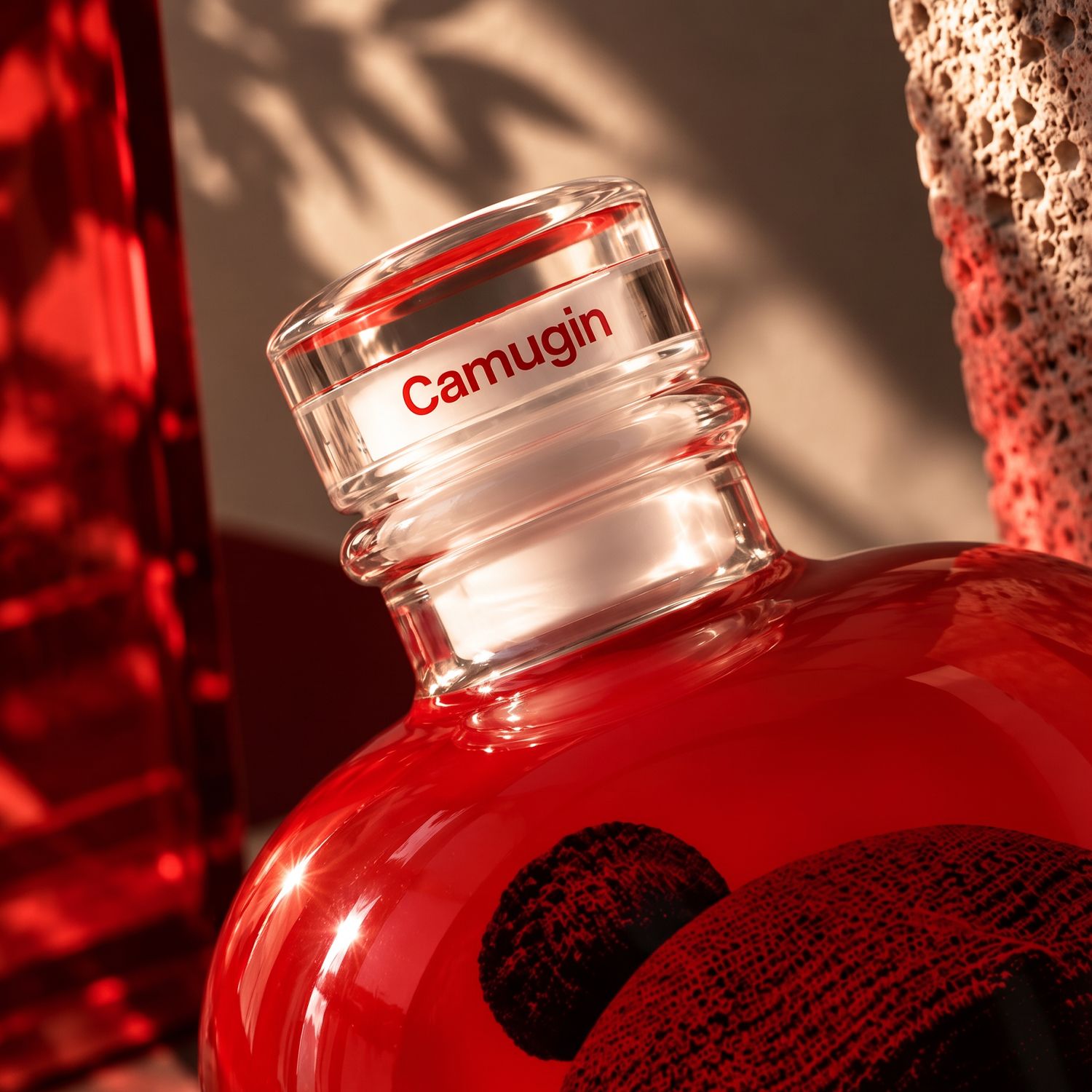 A close-up of Stone bottle by Berlin Packaging for Camugin surrounded by warm, textured surfaces and shadows.