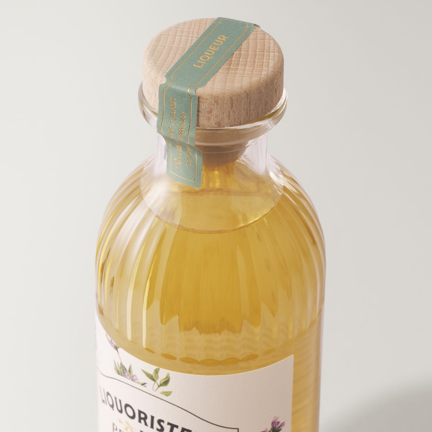 A close-up of Helium Ribs bottle by Berlin Packaging for Liquoristerie de Provence, filled with yellow liquid, sealed with a wooden cap and a green label bearing the word "Liqueur."
