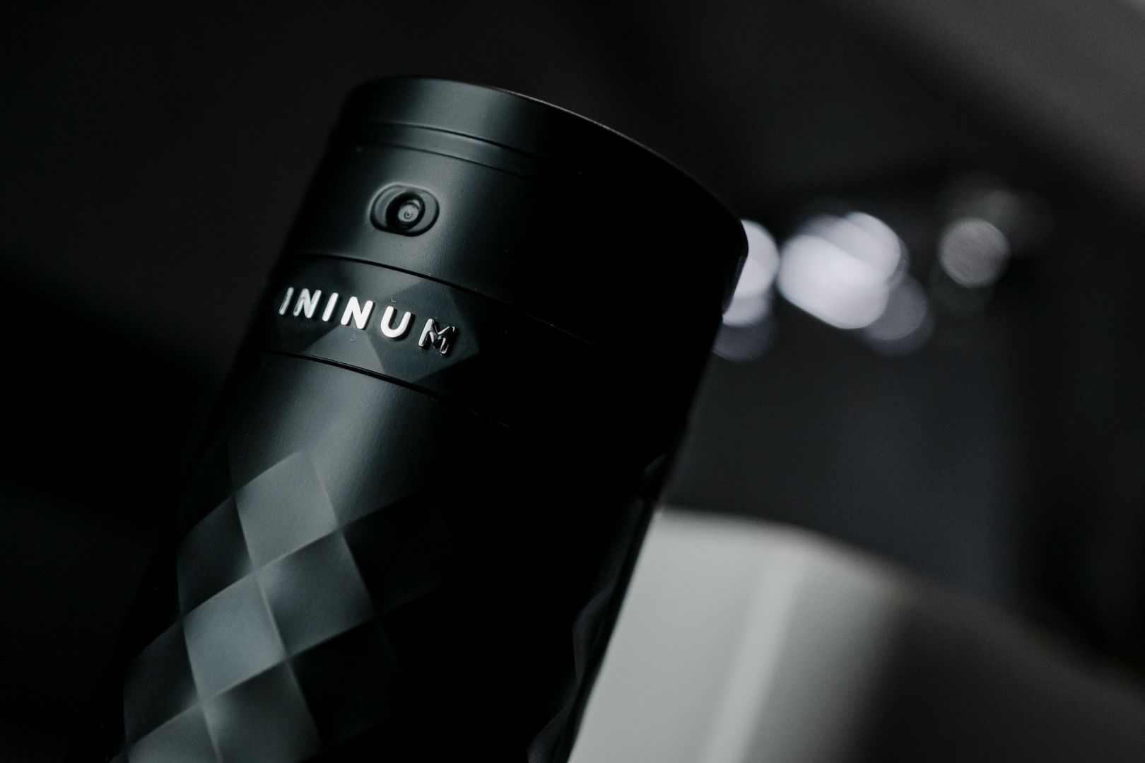 Ininum smart fragrance device by Berlin Packaging Beauty, close-up of the faceted black body with integrated power button and logo detail, showcasing premium design and connected fragrance technology.