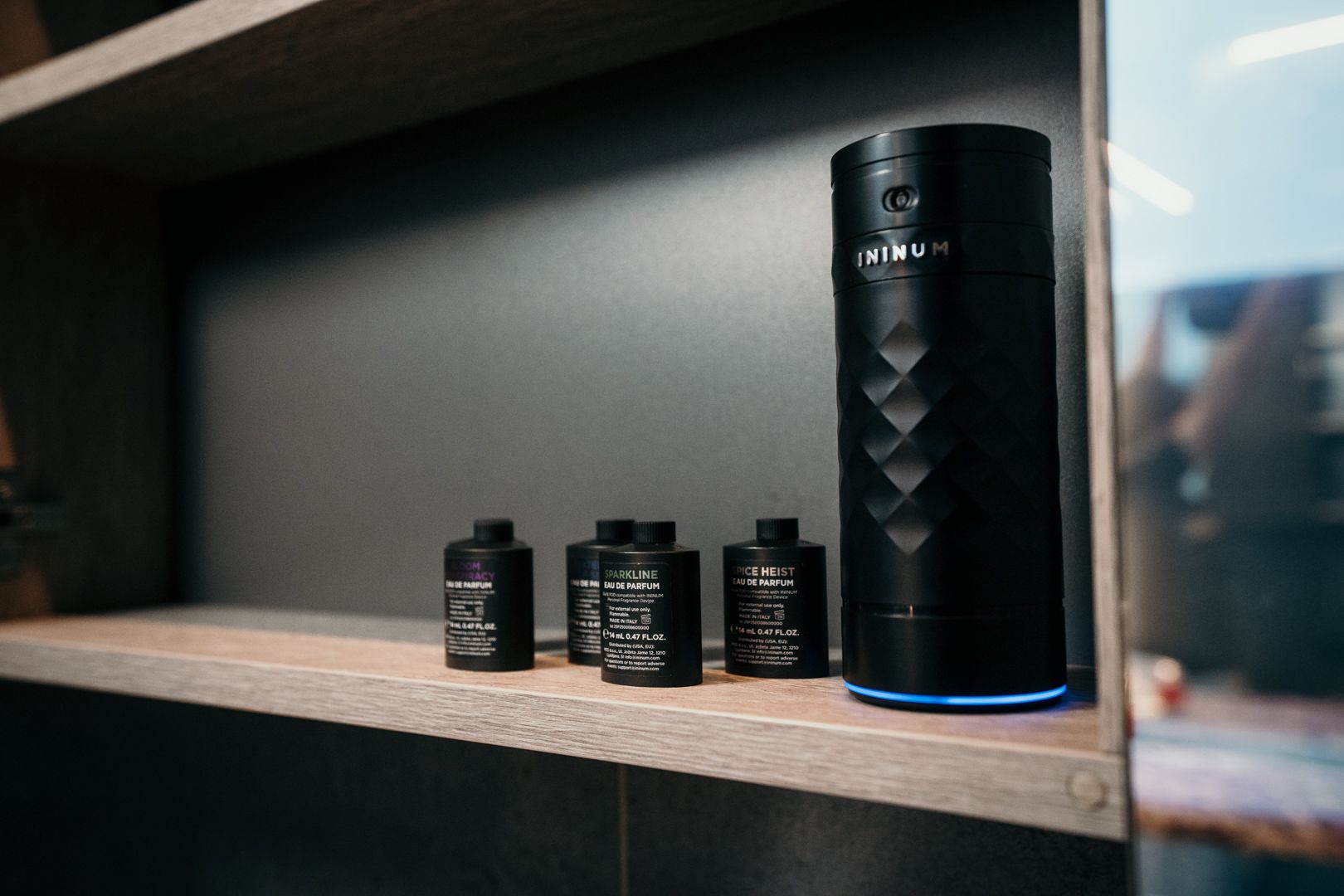 Ininum smart fragrance device by Berlin Packaging Beauty displayed with refill fragrance cartridges, featuring a faceted black design, illuminated base and interchangeable fragrance system for personalized scent experiences.