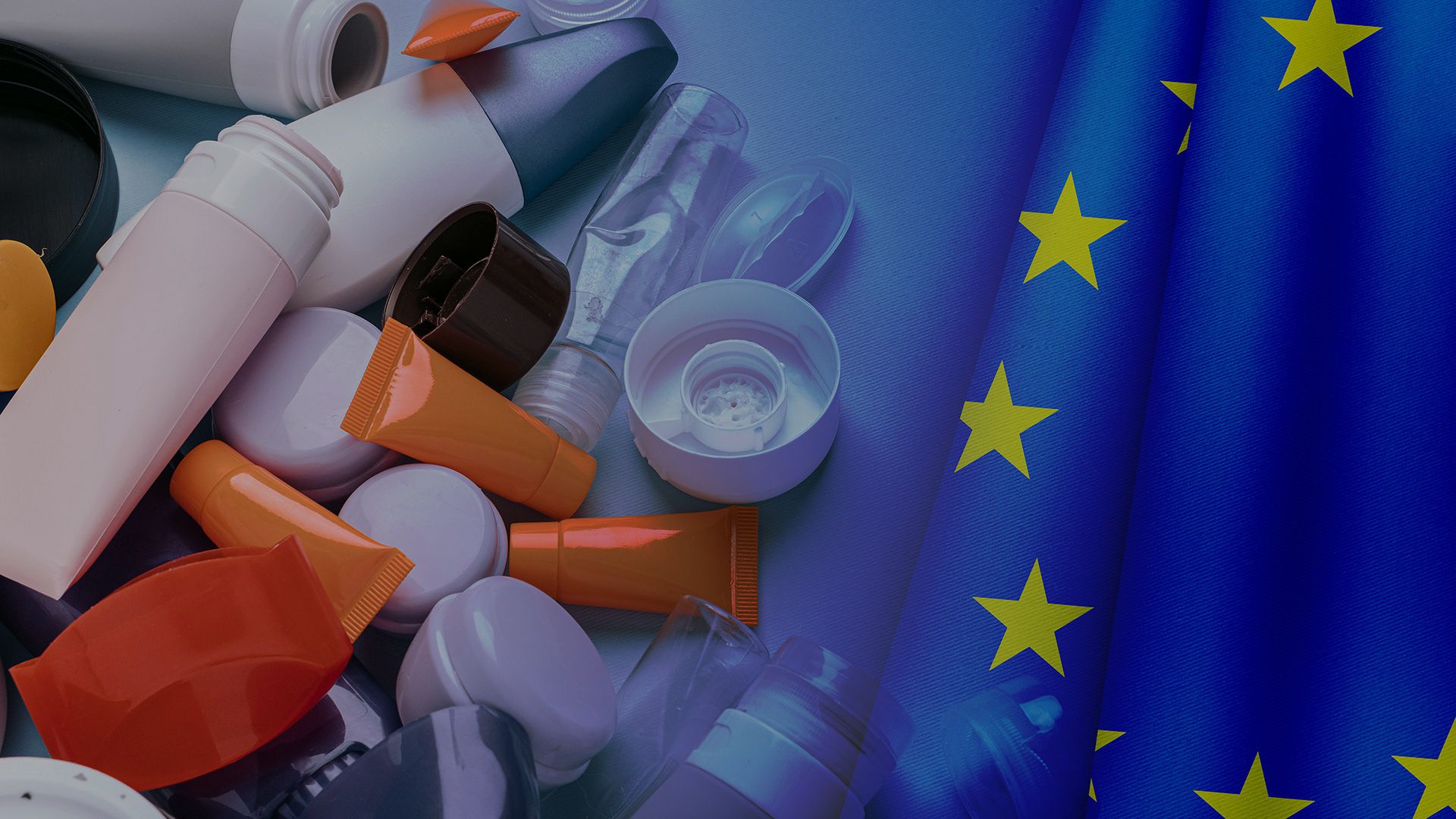 Various toiletries and cosmetics beside a European Union flag, symbolizing regulation or standards.