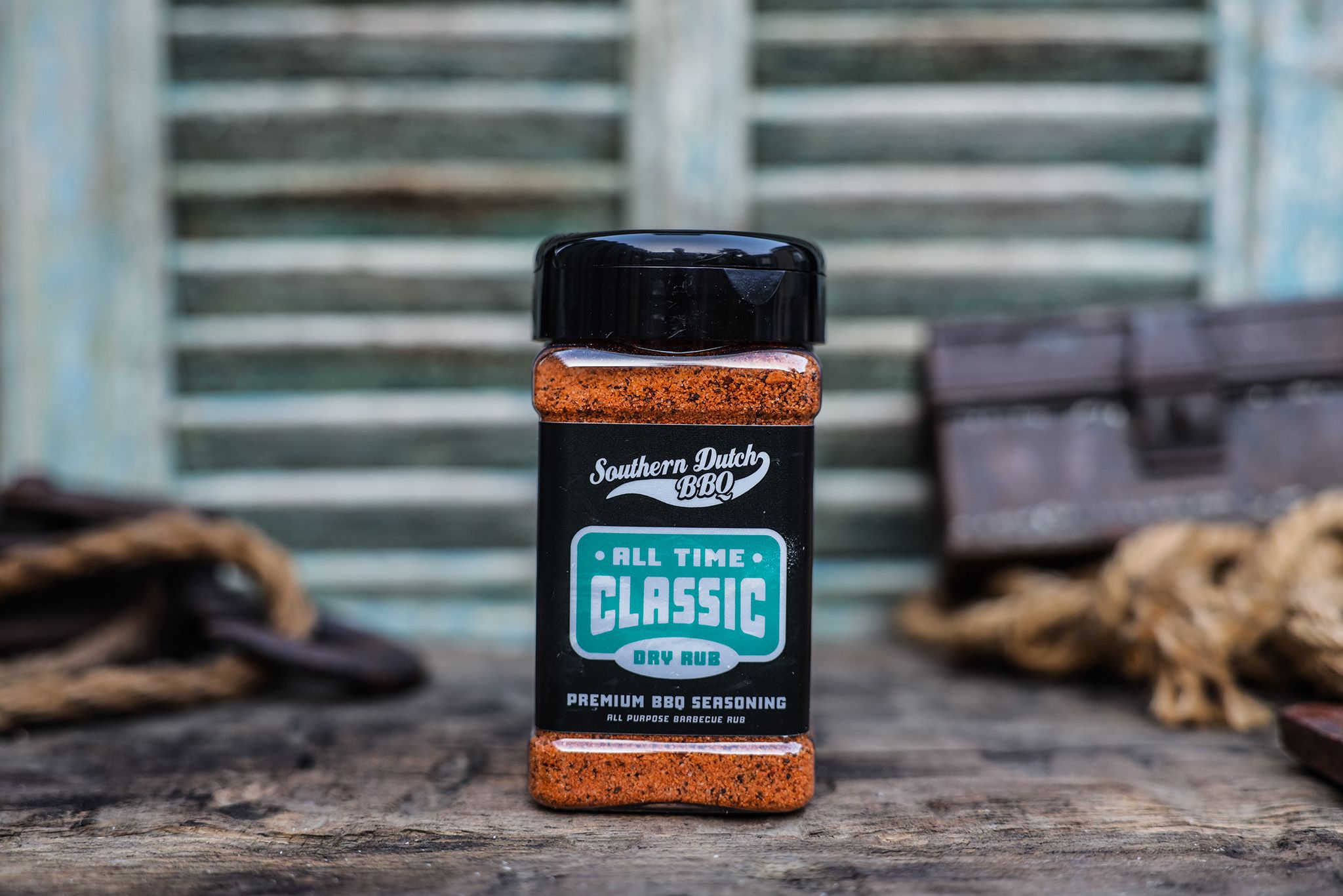 A bottle of Southern Dutch BBQ All Time Classic dry rub seasoning on a rustic wooden surface with a blurred background.