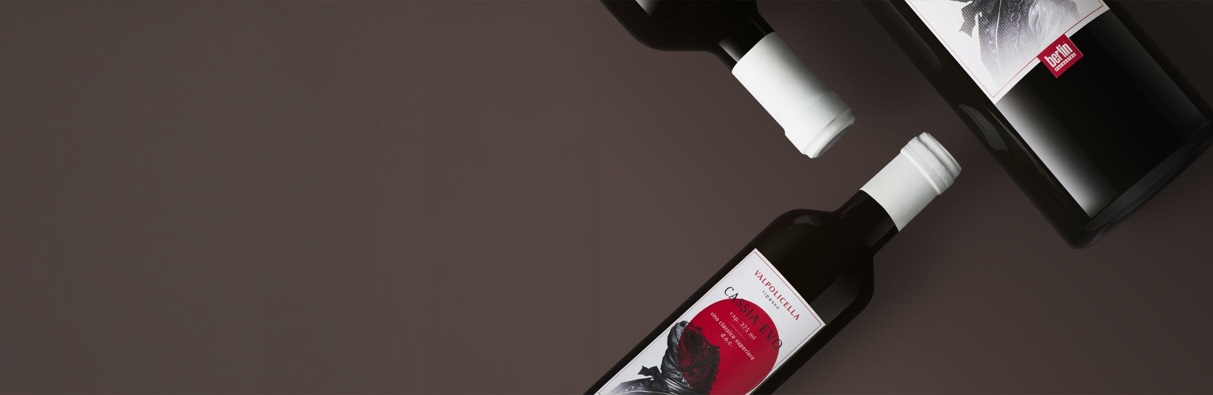 Cassia Evo Bottles collection for wine with white caps and decorative labels on a dark background, featuring red and black artwork.