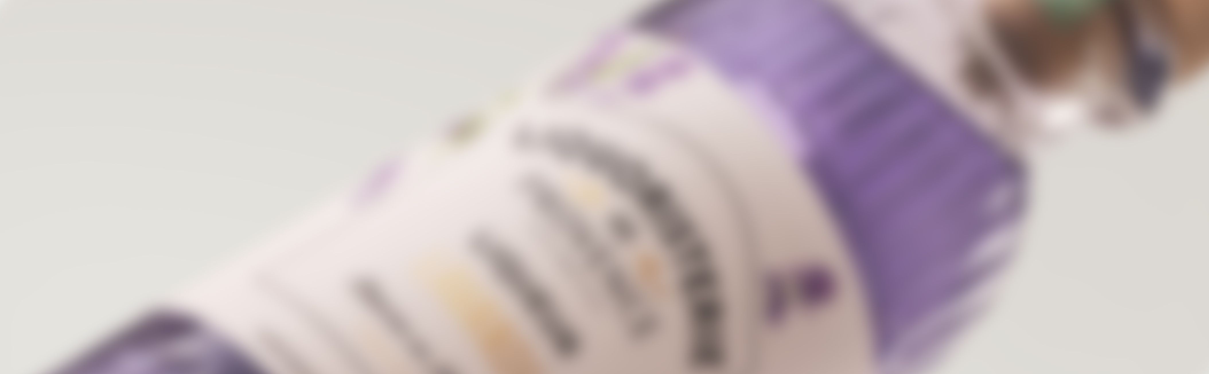 A blurry close-up of a Liquoristerie de provence bottle with a purple label and text, placed at an angle against a light background.