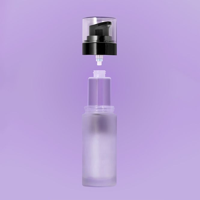 Close-up of an exploded view of an airless glass packaging on a purple background, showing the frosted glass container with the pump component separated above, highlighting the refillable and sustainable design concept.