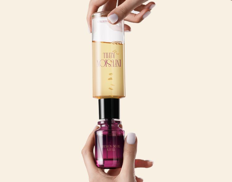 Infusion Fragrance Collection bottle by Berlin Packaging Beauty being refilled using a refill bottle with visible liquid, demonstrating reusable perfume packaging and sustainable refill system.