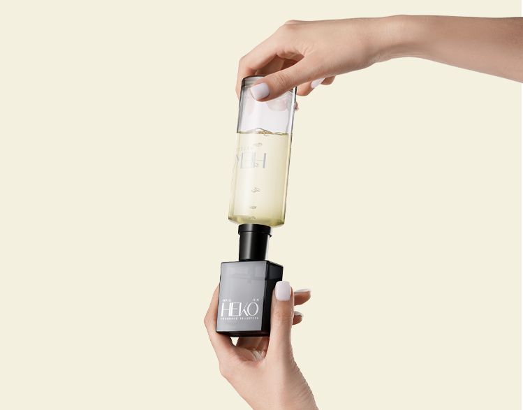 Heko Fragrance Collection bottle by Berlin Packaging Beauty being refilled using Neville refill bottle with visible liquid, demonstrating reusable fragrance packaging and sustainable refill system.
