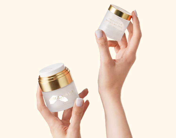Airglass Jar 50 ml by Berlin Packaging Beauty, refillable airless glass jar with removable inner refill held by hands, illustrating reusable cosmetic packaging and sustainable beauty refill system.