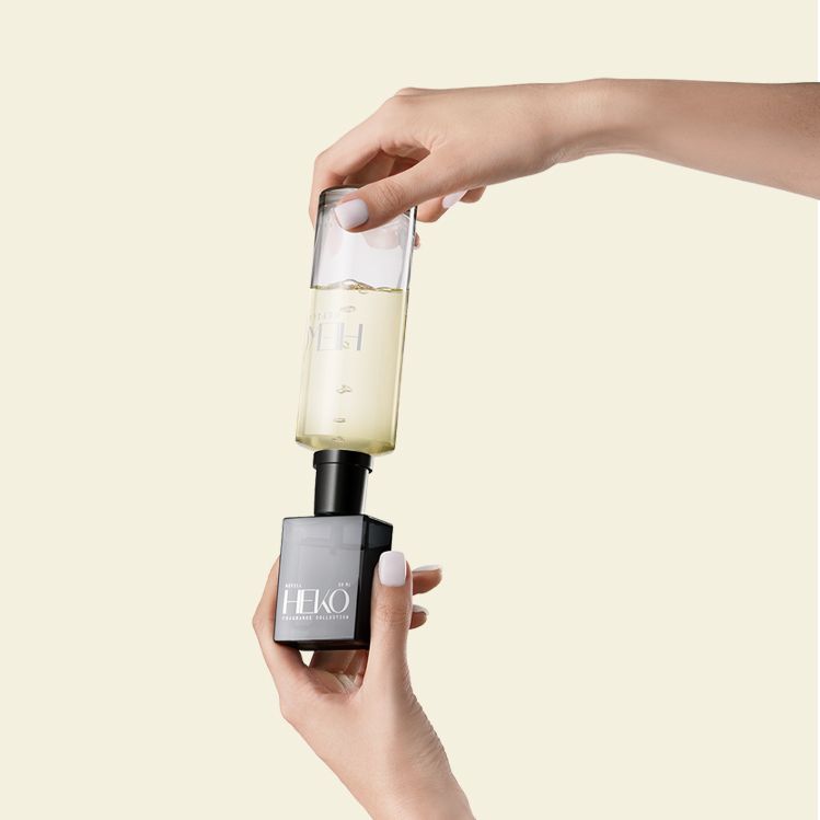 Heko Fragrance Collection bottle by Berlin Packaging Beauty being refilled using Neville refill bottle with visible liquid, demonstrating reusable fragrance packaging and sustainable refill system.