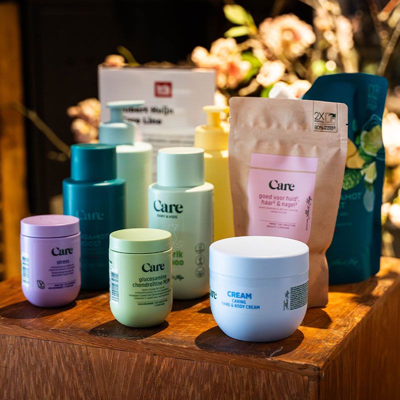 Assorted skincare and wellness products on a wooden table, with bottles and containers in various pastel colors, surrounded by soft lighting.