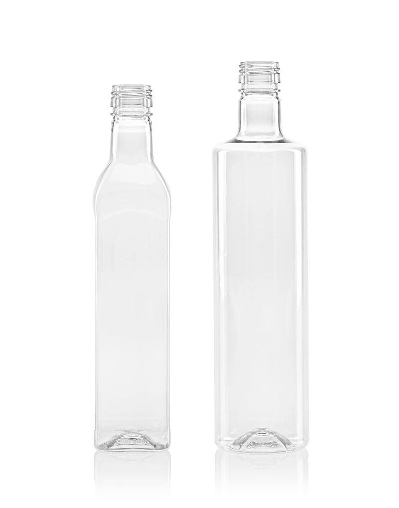 Two clear, empty glass bottles standing side by side on a reflective white surface.
