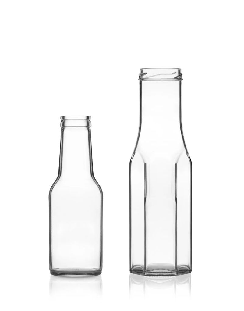 Two transparent glass bottles on a white background; one short and round, the other tall with a hexagonal base.