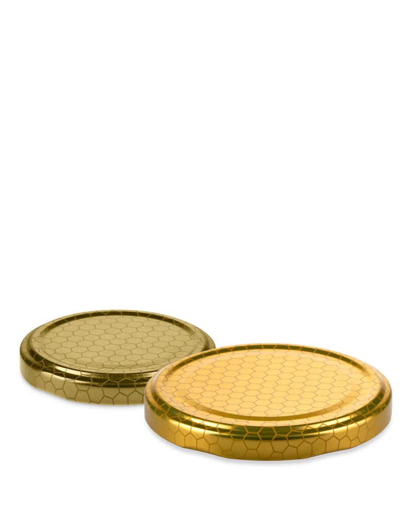 Two golden honeycomb-patterned jar lids lying on a white background, one slightly overlapping the other.