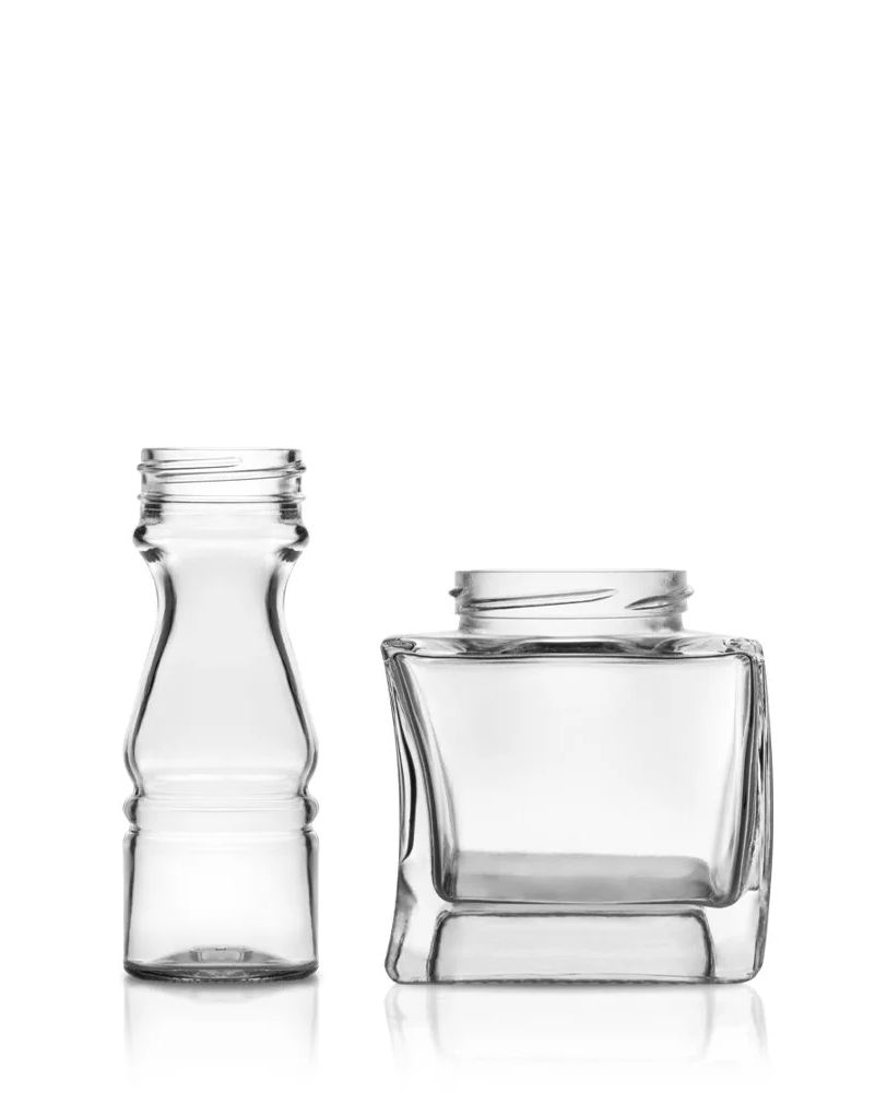 Two empty, clear glass bottles: one tall and narrow, the other short and square, both without lids, on a white background.