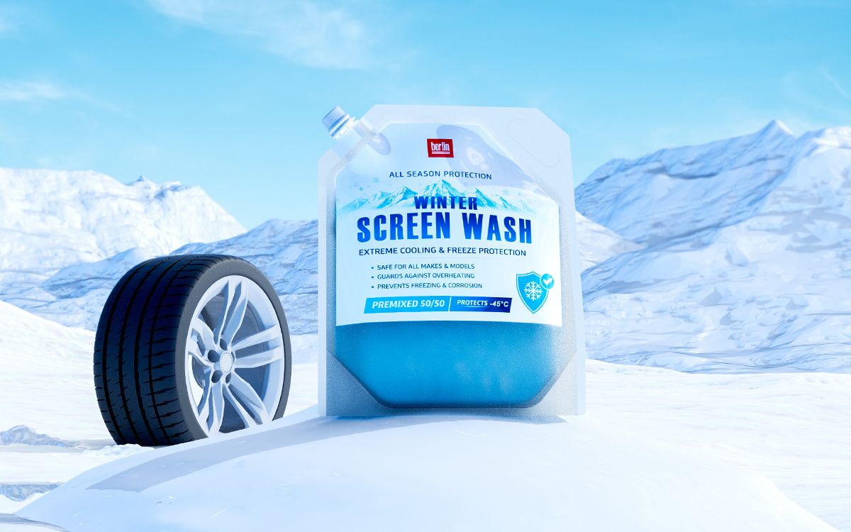 A jug of antifreeze on snowy terrain next to a car tire, with mountains in the background. The label highlights protection and safety features.