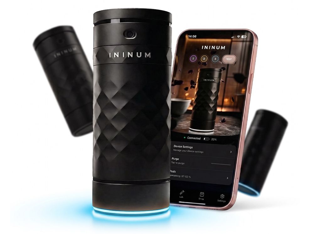Ininum smart fragrance device by Berlin Packaging Beauty displayed with mobile app integration, featuring a faceted black design, illuminated base and connected technology for personalized fragrance experiences.