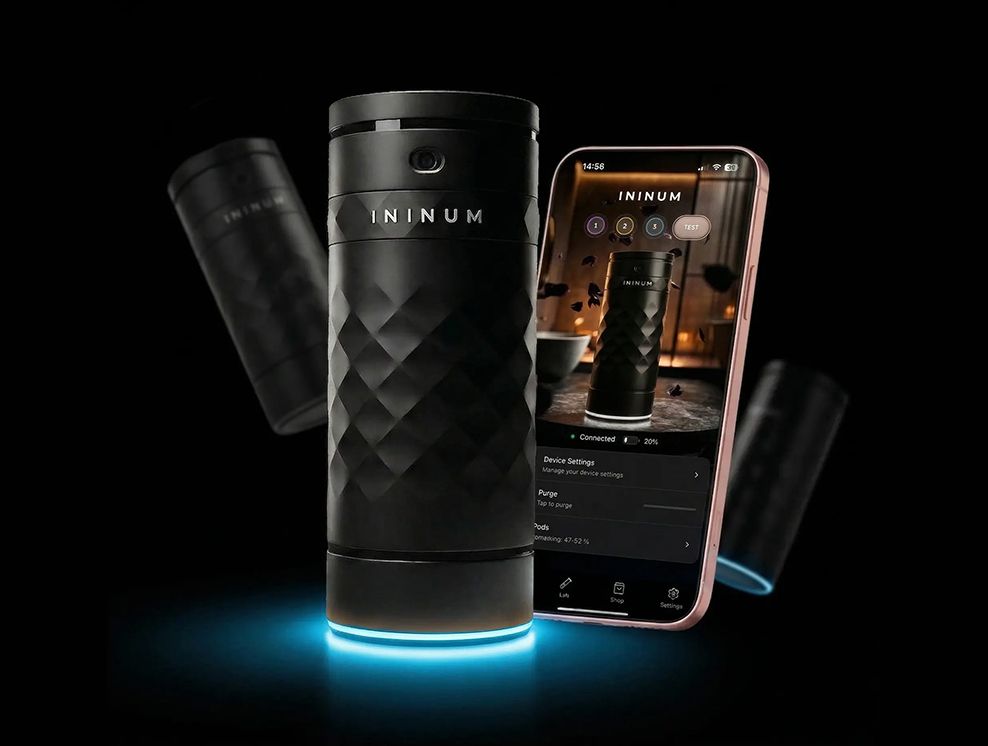 Ininum smart fragrance device by Berlin Packaging Beauty displayed with mobile app integration, featuring a faceted black design, illuminated base and connected technology for personalized fragrance experiences.