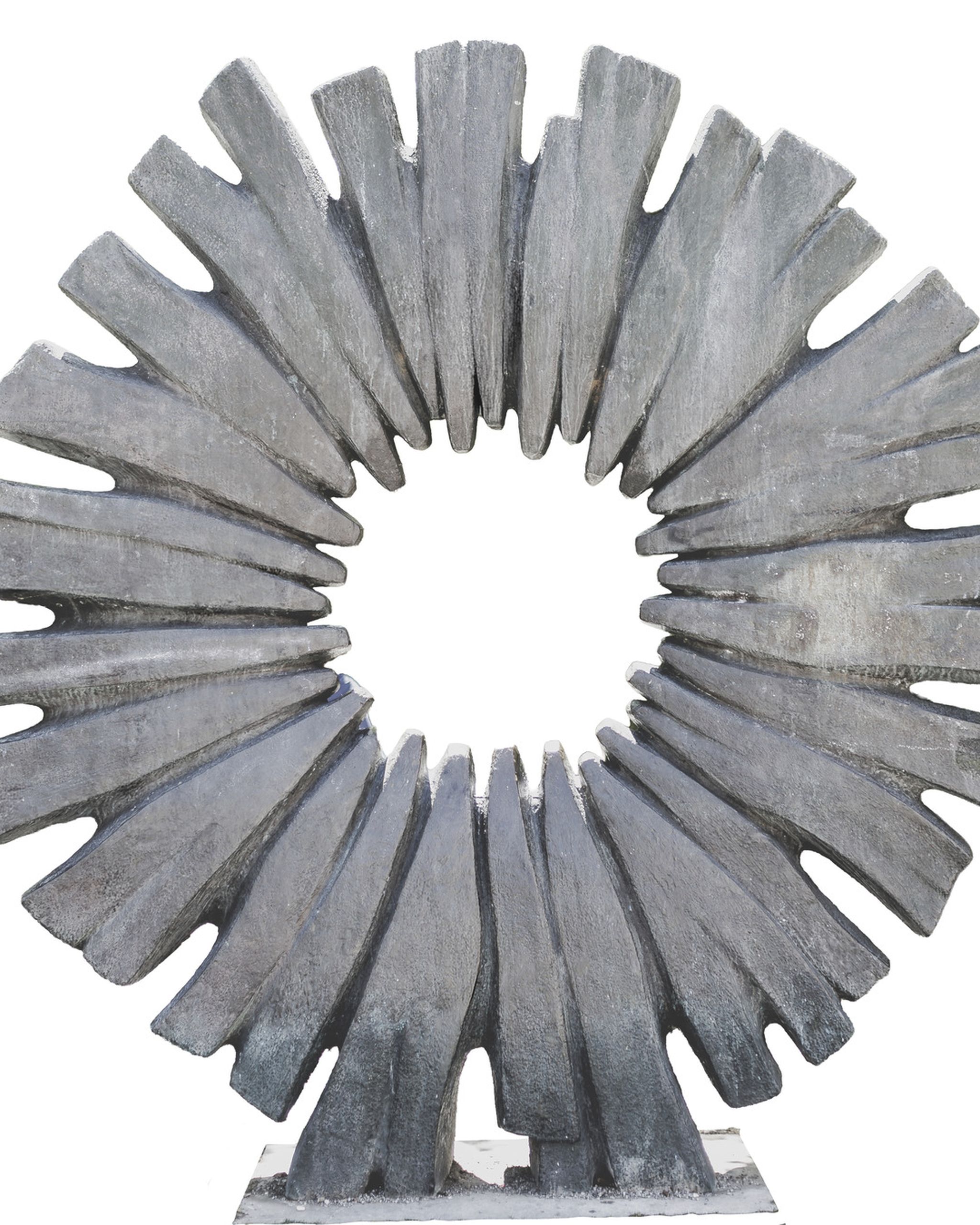 A large, circular stone sculpture with jagged, radiating segments converging toward an open center.