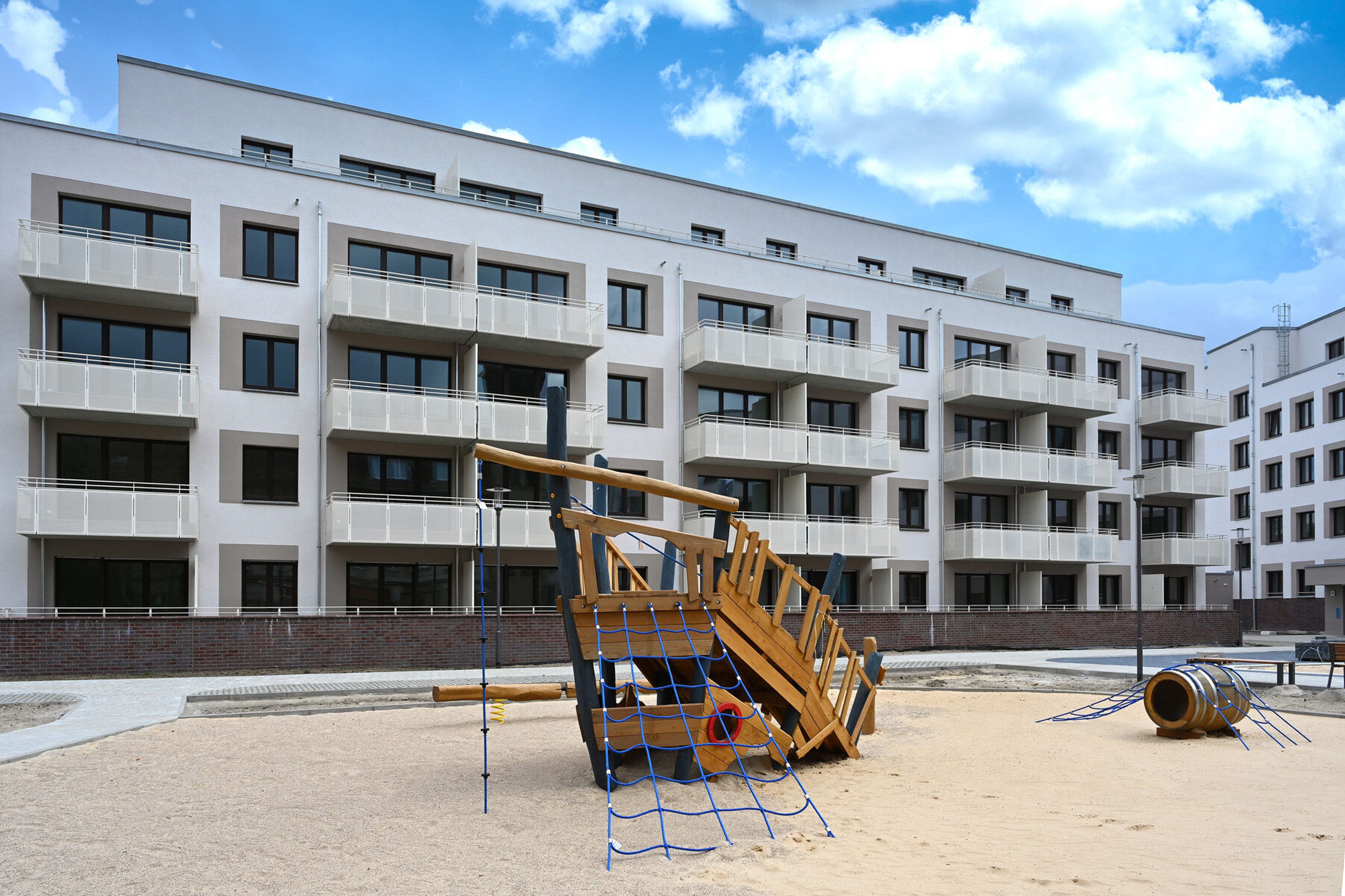 Spielplatz mit Klettergerüst vor einem modernen Wohngebäude.