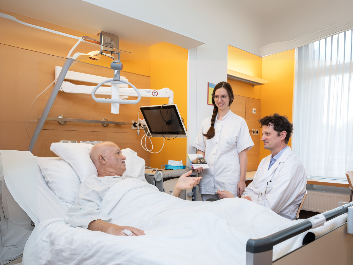 Arzt und Assistentin bei Patienten im Zimmer
