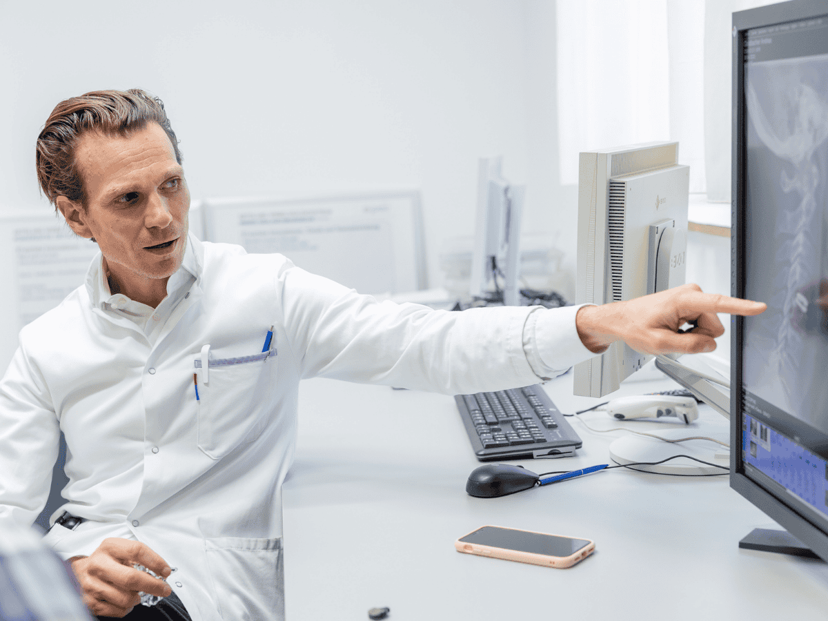 Arzt zeigt auf Röntgenbild am Bildschirm