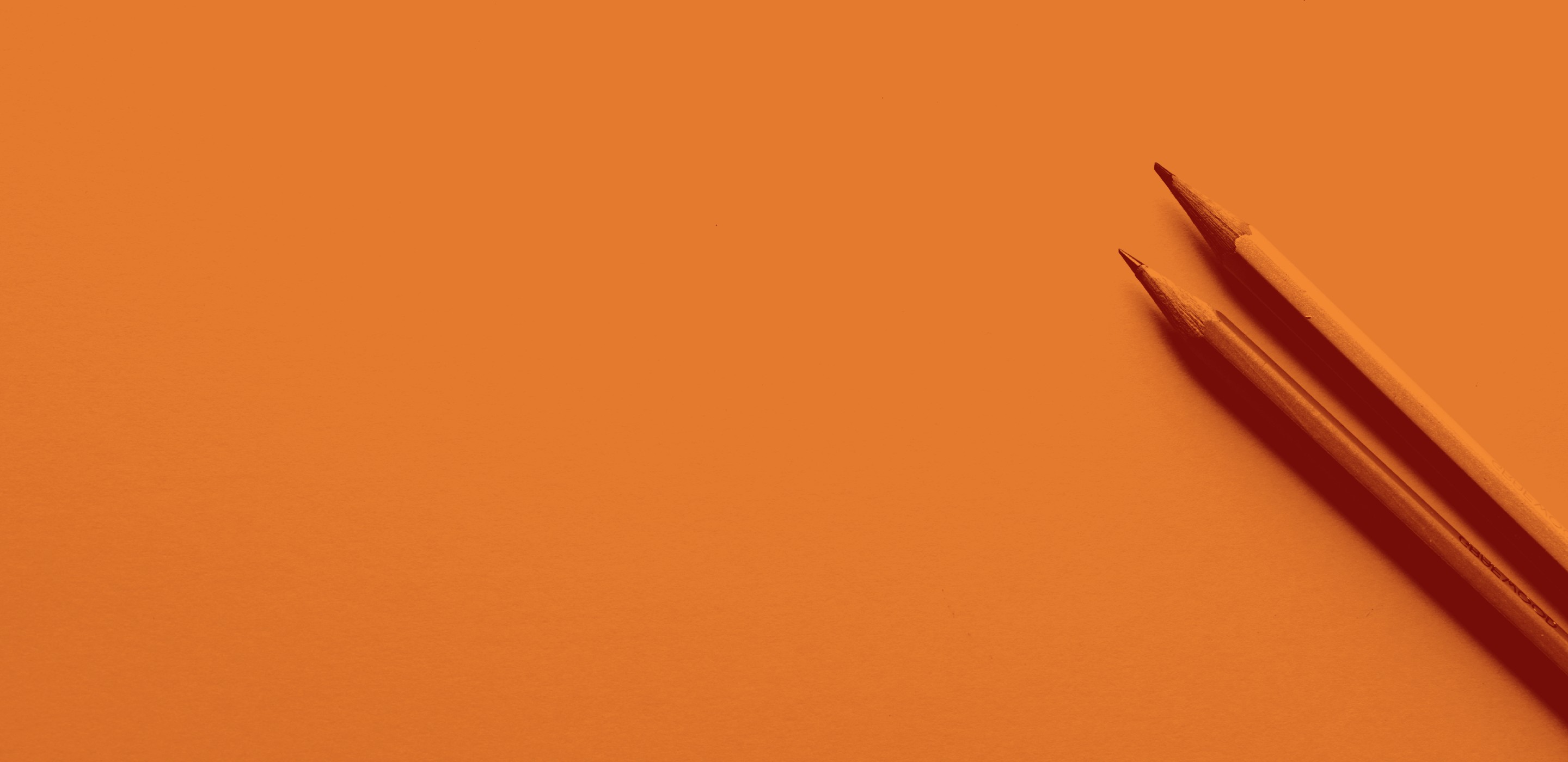 Zwei Bleistifte auf orangem Hintergrund. Sie ragen schräg in das Bild.