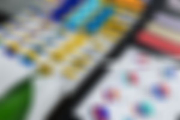 Color swatches, an iPad with color sketches, and an Apple computer on a desk, indicating a design workspace.