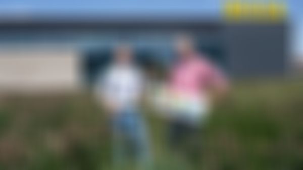 Zwei Personen in einem Feld mit Blumen vor einem Billa Geschäft