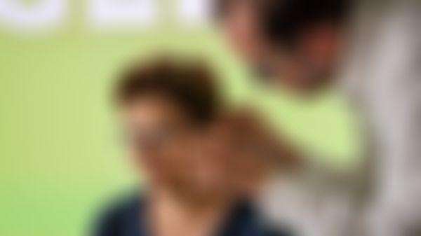 Ein Mann setzt vorsichtig ein Geers-Hörgerät in das Ohr einer Frau ein bzw. richtet es passend aus.