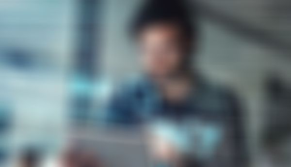 Ein Mann mit Brille benutzt ein Tablet, umgeben von digitalen Datenprojektionen, darunter Grafiken, Binärcode und eine Weltkarte.