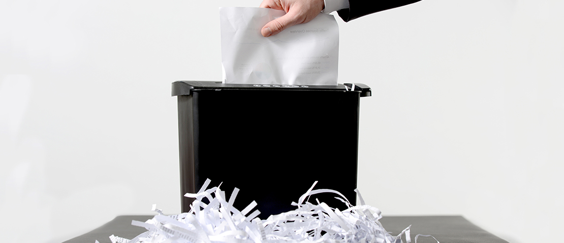 Aktenvernichter mit geschredderten Papierstreifen zur DSGVO-konformen Dokumentenvernichtung