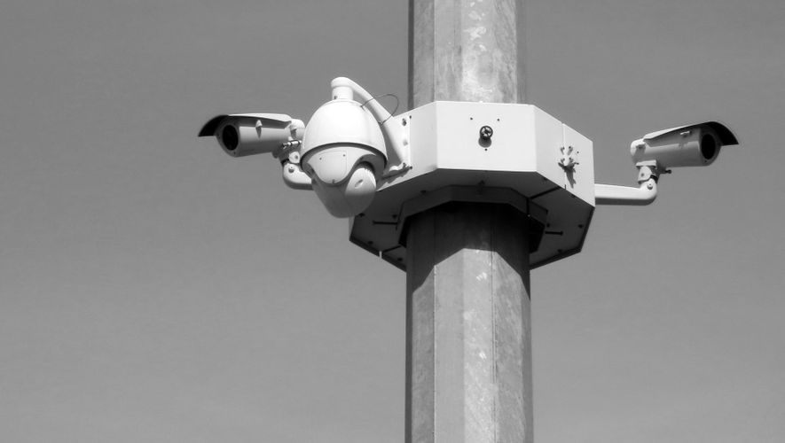 Czarno-biały obraz przedstawiający system kamer monitorujących zamontowany na słupie, składający się z wielu kamer skierowanych w różnych kierunkach.