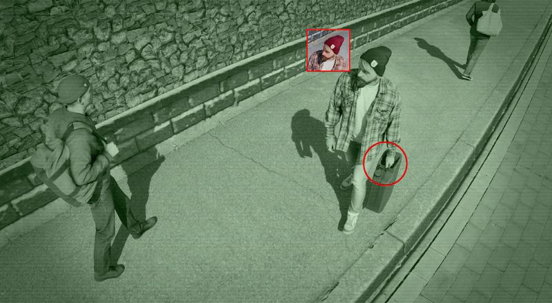 Image de surveillance de rue montrant trois personnes marchant sur un trottoir. Un individu est mis en évidence avec un carré rouge et tient une mallette entourée en rouge.